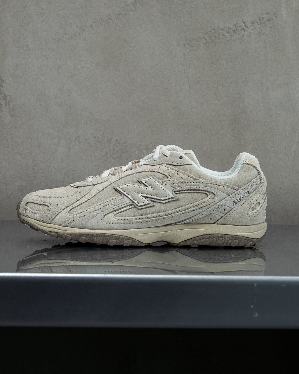 White New Balance sneaker on a reflective surface with a gray background